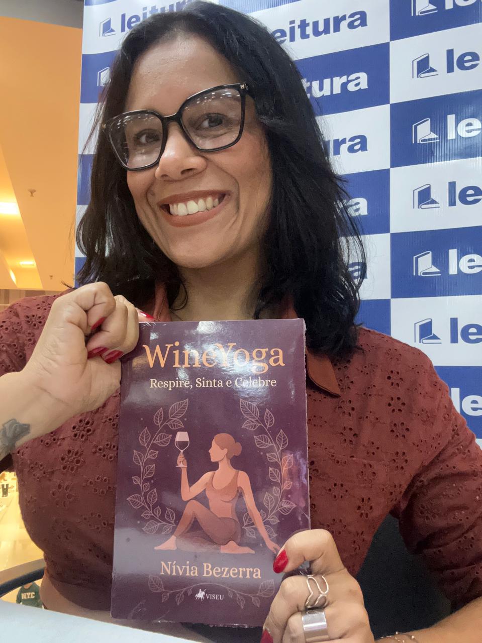 Nívia segurando o livro WineYoga